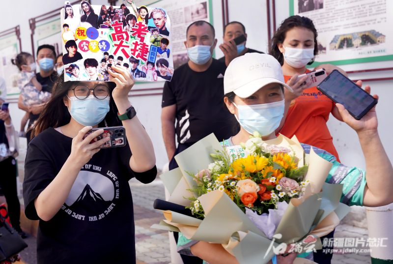 6月8日下午，乌鲁木齐八一中学考点，两位女士抱着鲜花、举着“明星”迎接自家考生。石榴云/新疆日报记者张万德摄