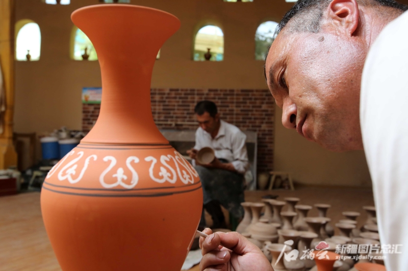 6月19日，恰克日库依村土陶制作艺人伊马木·艾力在土陶罐上画画。石榴云/新疆日报记者 蔡增乐 摄