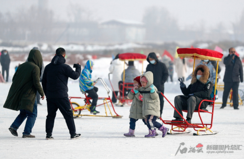 2022年2月2日，兵团第十二师头屯河谷森林公园内的冰场上，各族群众正拉着冰上雪橇和家人一起游戏。 石榴云/新疆日报记者秦鹏摄